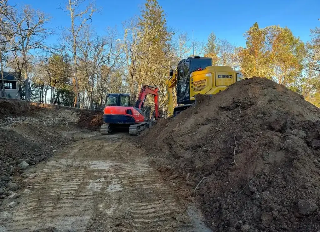 Excavators moving dark soil.